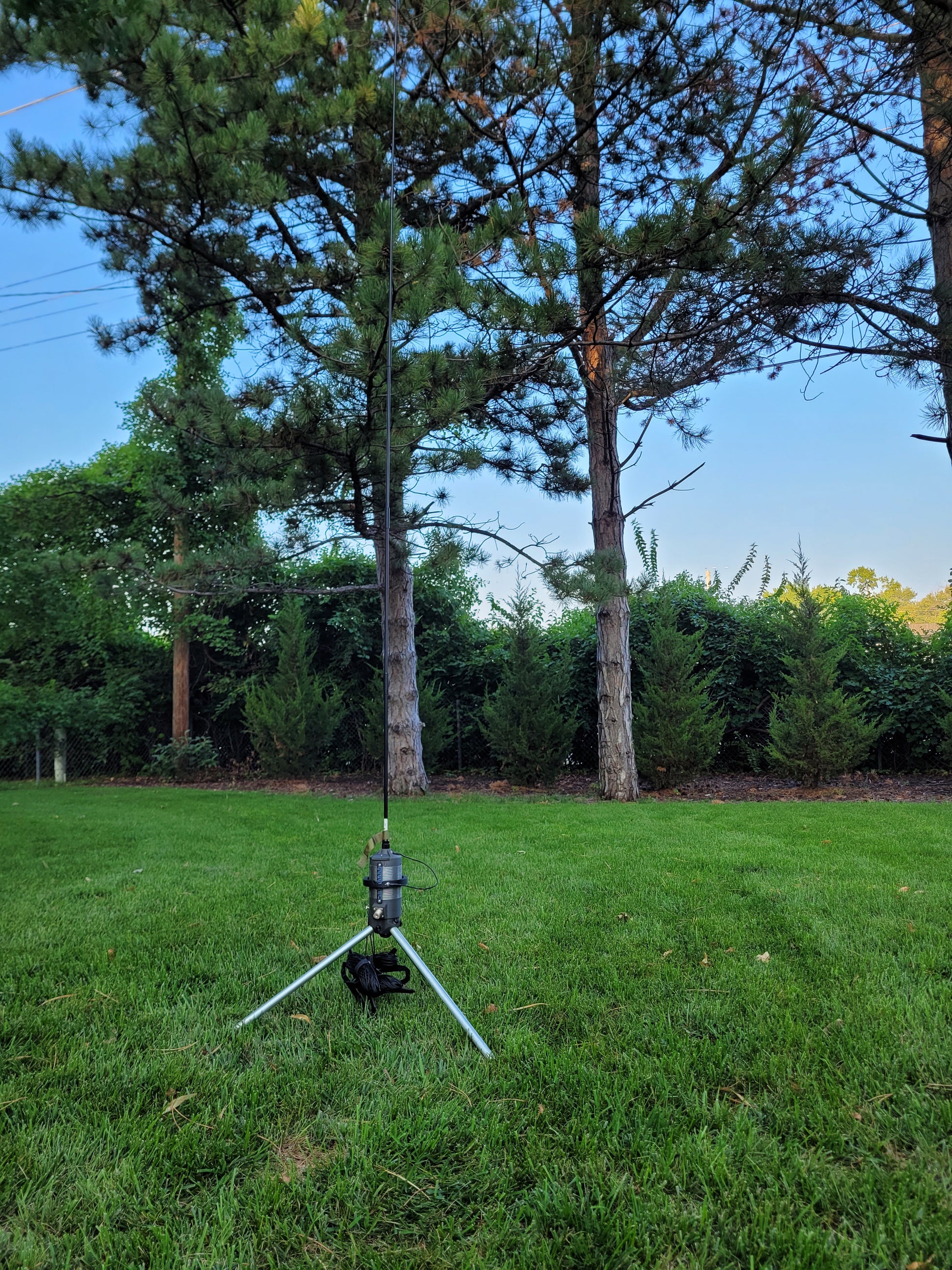 Big Kansas Coil and Whip sitting on tripod with wire radials in green grass